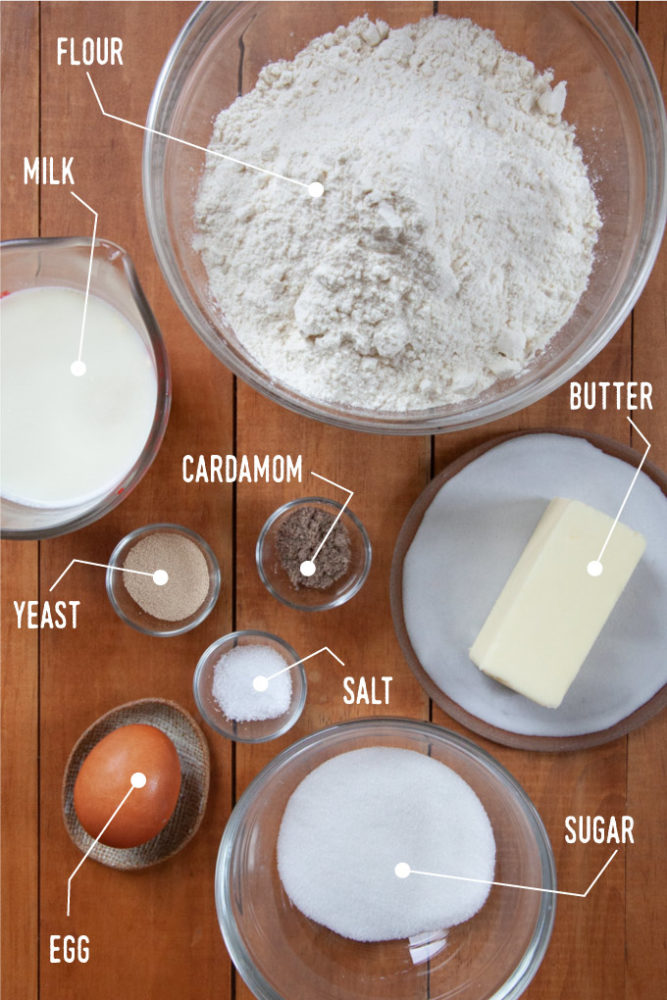 Ingredients for the Swedish semla dough, including flour, butter, sugar, salt, yeast, milk, egg and cardamom, all in bowls.