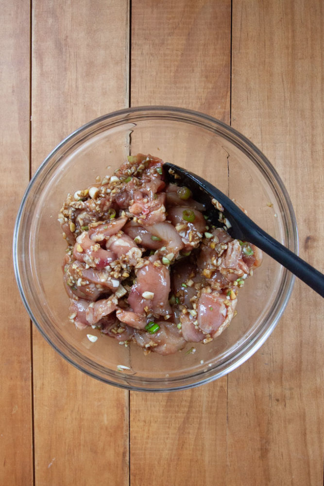 Chicken in a bowl of soy sauce marinade.