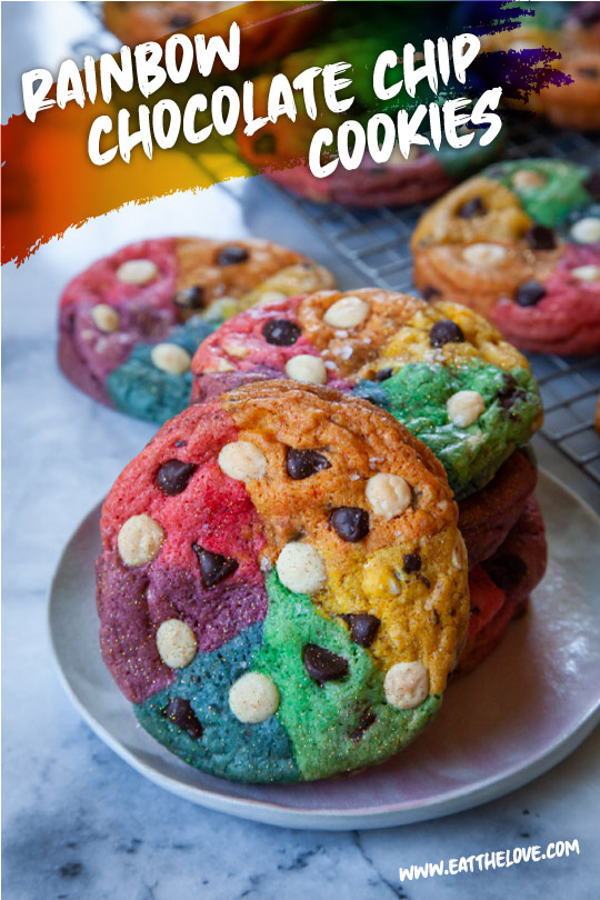 A plate of rainbow chocolate chip cookies with more rainbow chocolate chip cookies behind it.