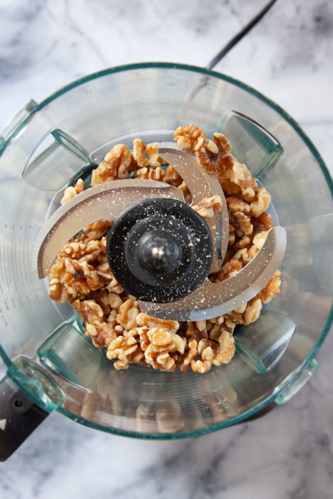 Walnut pieces in a food processor bowl.