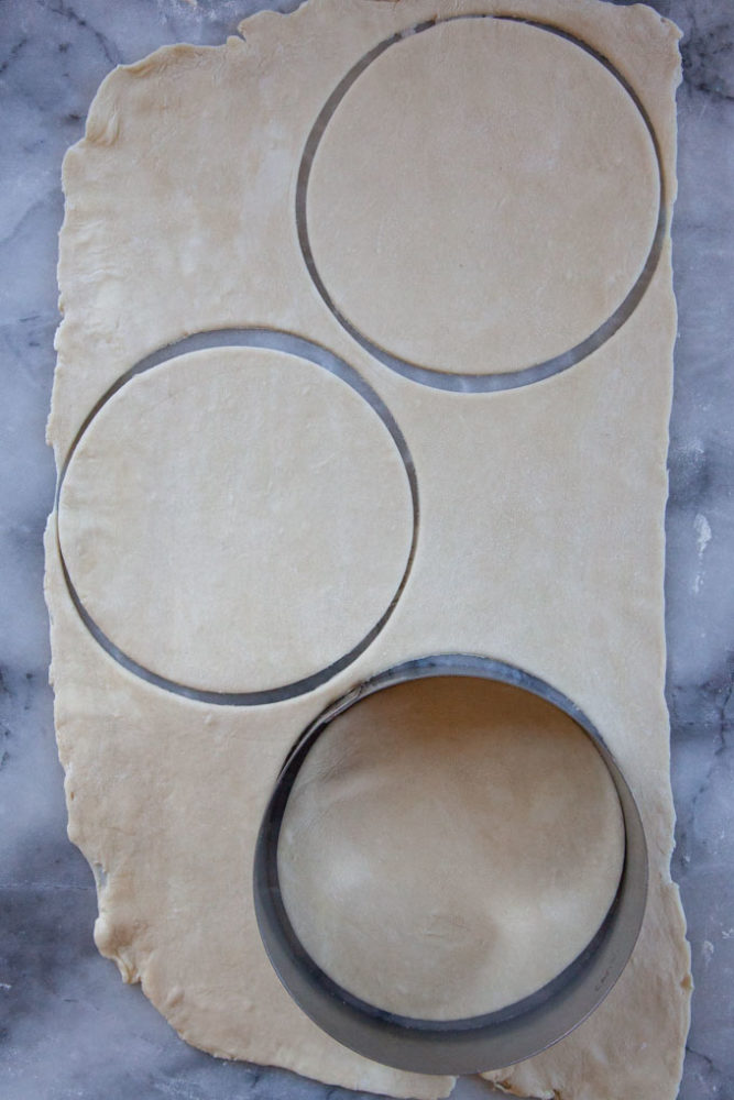 Hand pie dough rolled out with circles cut out from them.