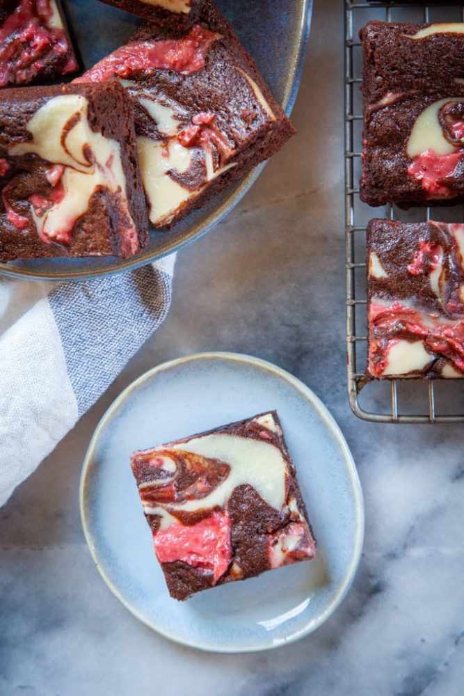 A Neapolitan flavored brownie on a small blue plate with more brownies next to it.