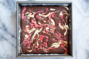 Neapolitan brownies baked in a pan sitting on a marble surface.