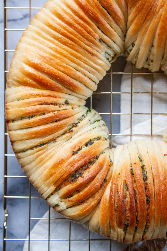 Herb wool roll bread on a wire cooling rack.