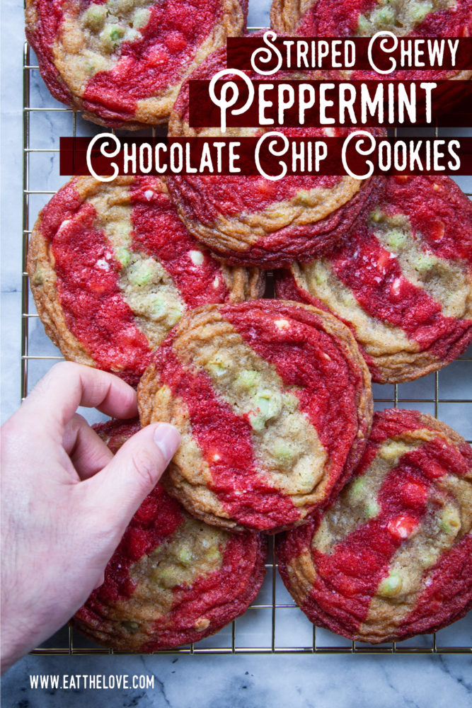 A hand reaching for a striped chewy peppermint chocolate chips cookie stacked on a wire cooling rack.