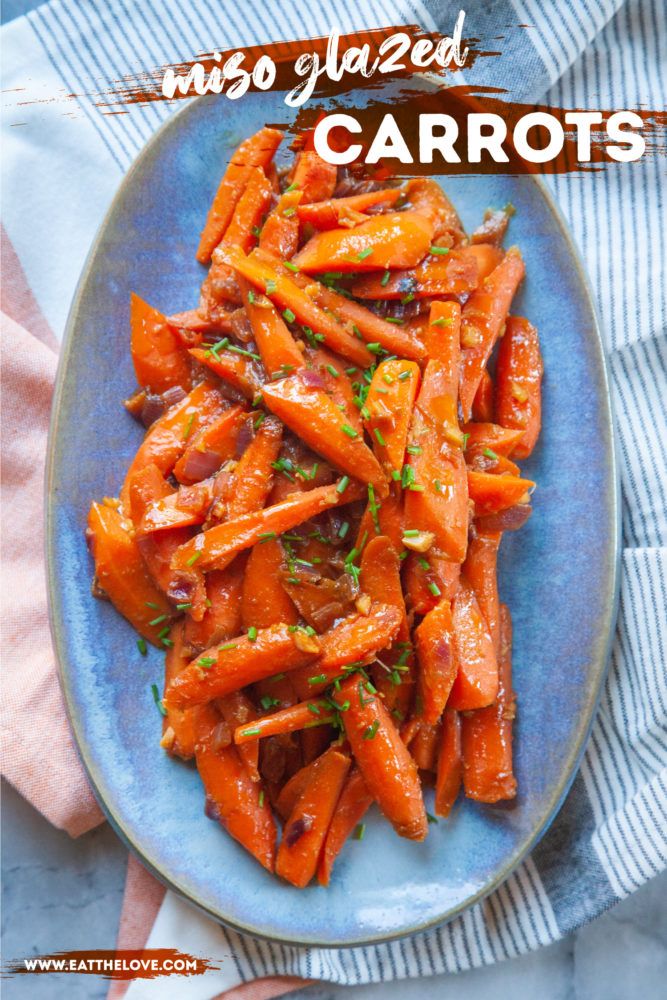 A blue plate of miso glazed carrots topped with chopped green chives.