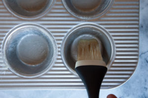 A brush with coating a muffin pan with melted butter