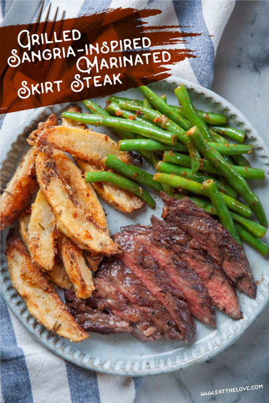 A plate with sangria marinated grilled skirt steak, potato wedges and green beans.