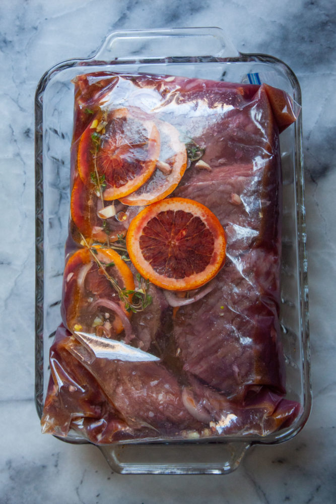 Skirt steak and sangria marinade in a sealed 2 gallon ziplock bag placed in a glass baking pan.