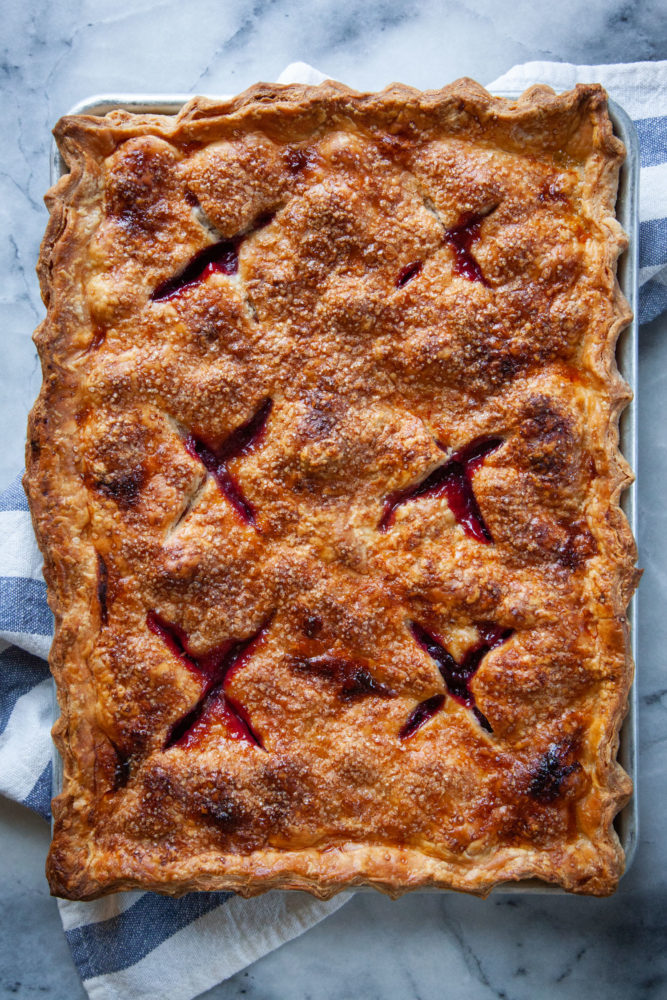 A baked cherry slab pie on a kitchen towel. 