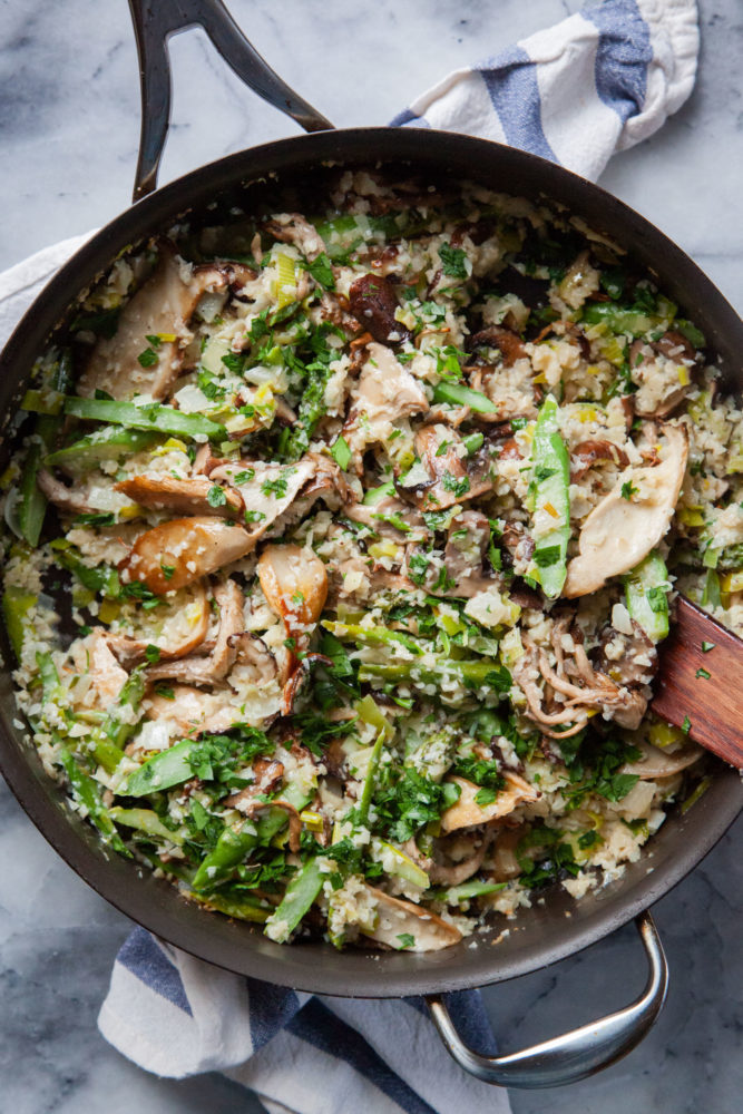 A large saute pan filled with cauliflower risotto with wild mushrooms and asparagus.