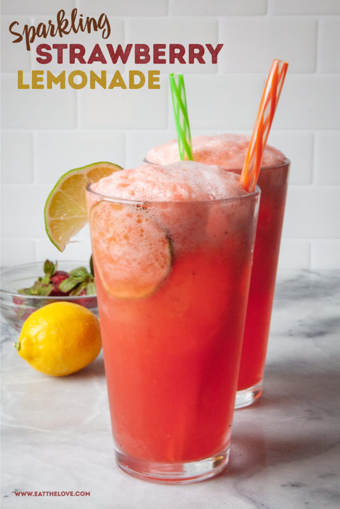 Two glasses of sparking strawberry lemonade with straws sticking out of them. A lemon and a bowl of strawberries are behind them.