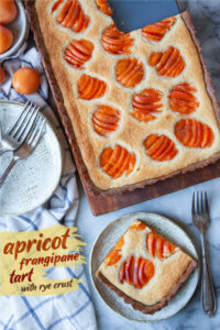 A slice of apricot frangipane on a plate, with the remaining tart next to it.