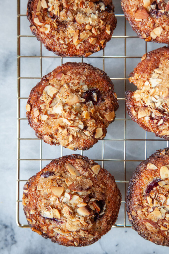 Cherry almond muffins on a wire cooling rack.