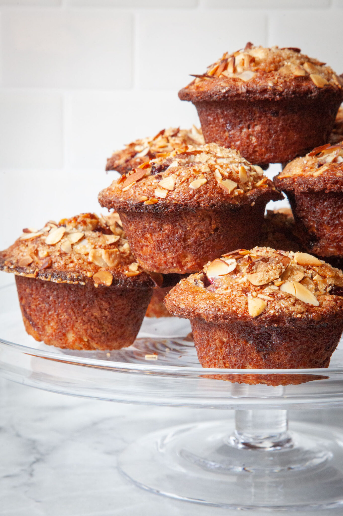 A stack of cherry almond muffins on a cake stand.
