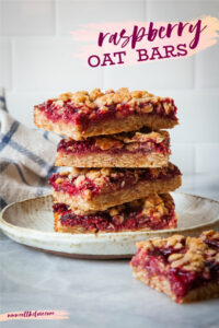 A stack of raspberry oat bars on a plate, with one more raspberry oat bar on the table in front of it.