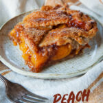 A piece of peach slab pie on a plate with a fork next to it.