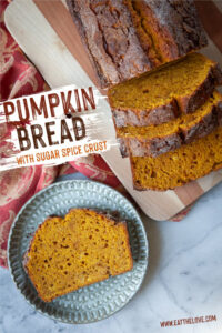 A slice of pumpkin bread on a plate, with the remaining pumpkin bread next to it on a cutting board.