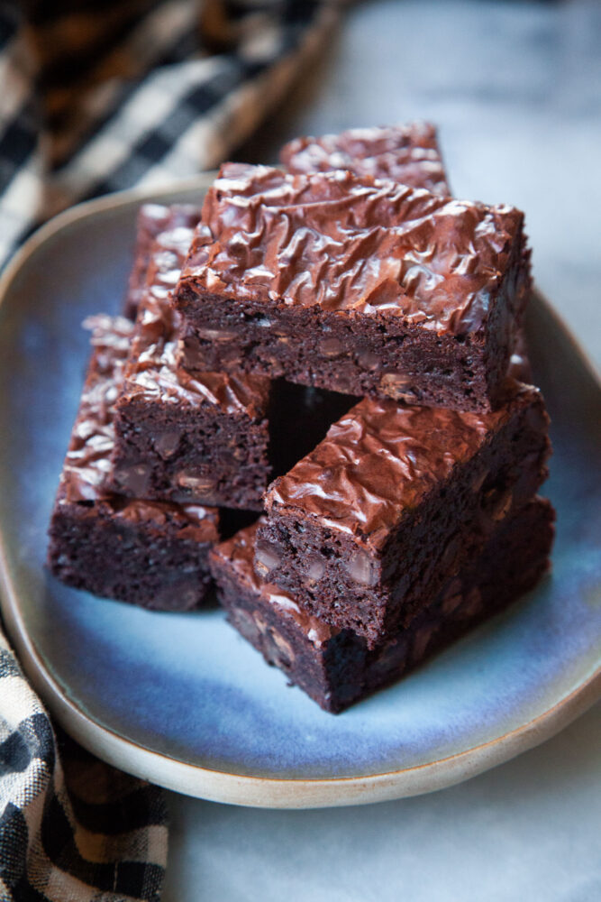 A stack of fudge brownies on a blue plate.
