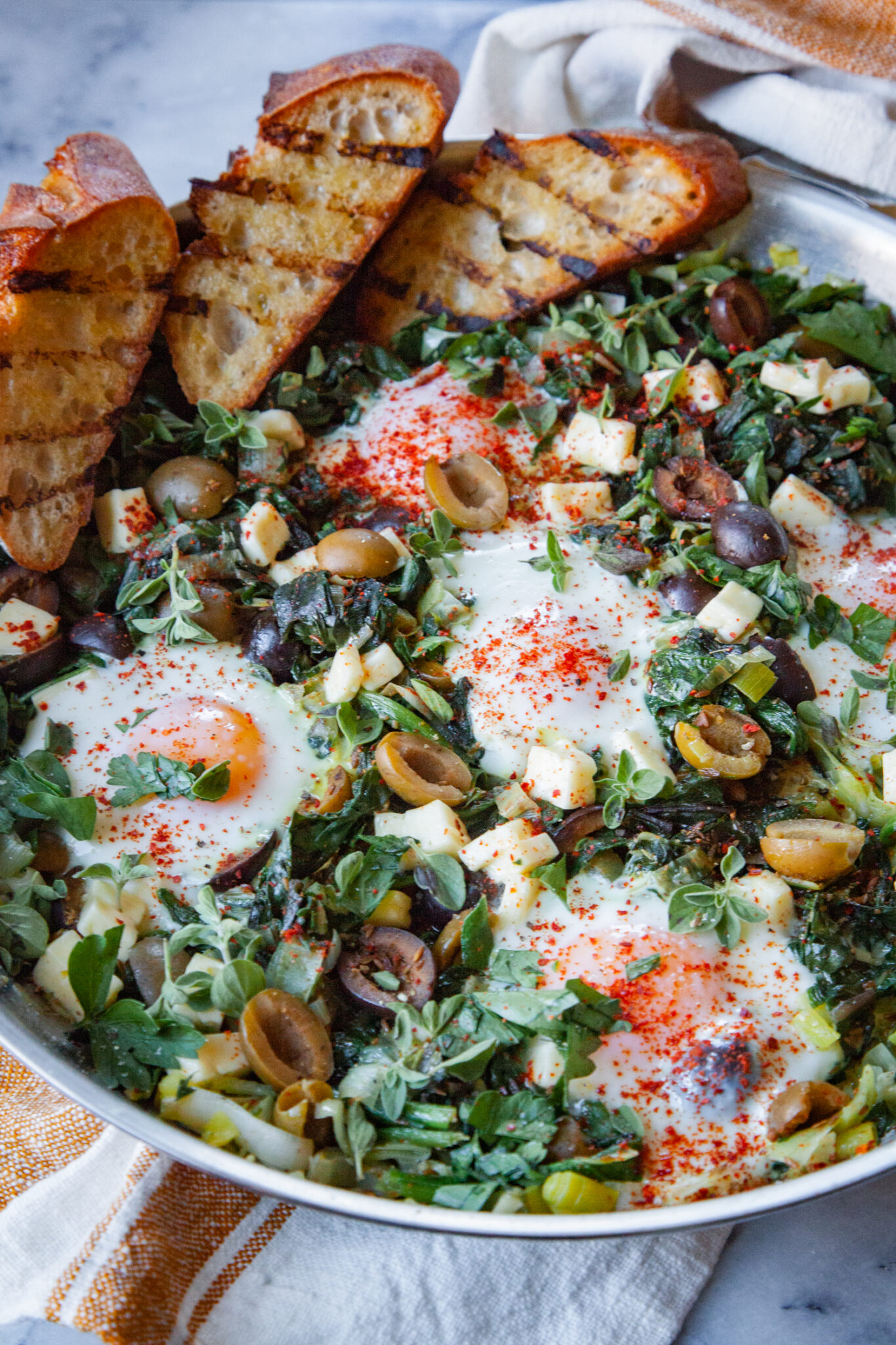 A pan of green shakshuka with toast tucked into the edges of the pan.