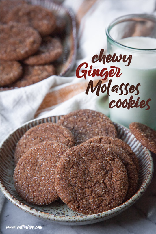 Chewy ginger molasses cookies on a ceramic plate, with a glass of milk behind it, and another plate of more ginger molasses cookies in the background.