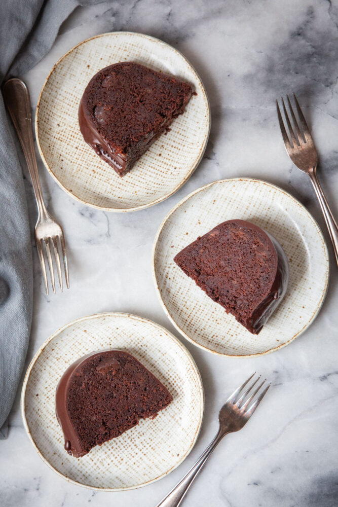 Three small dessert plates, each with a slice of Guinness chocolate bundt cake on them.