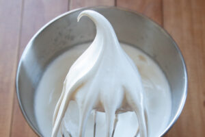 A wire whisk showing stiff peaks for the meringue.