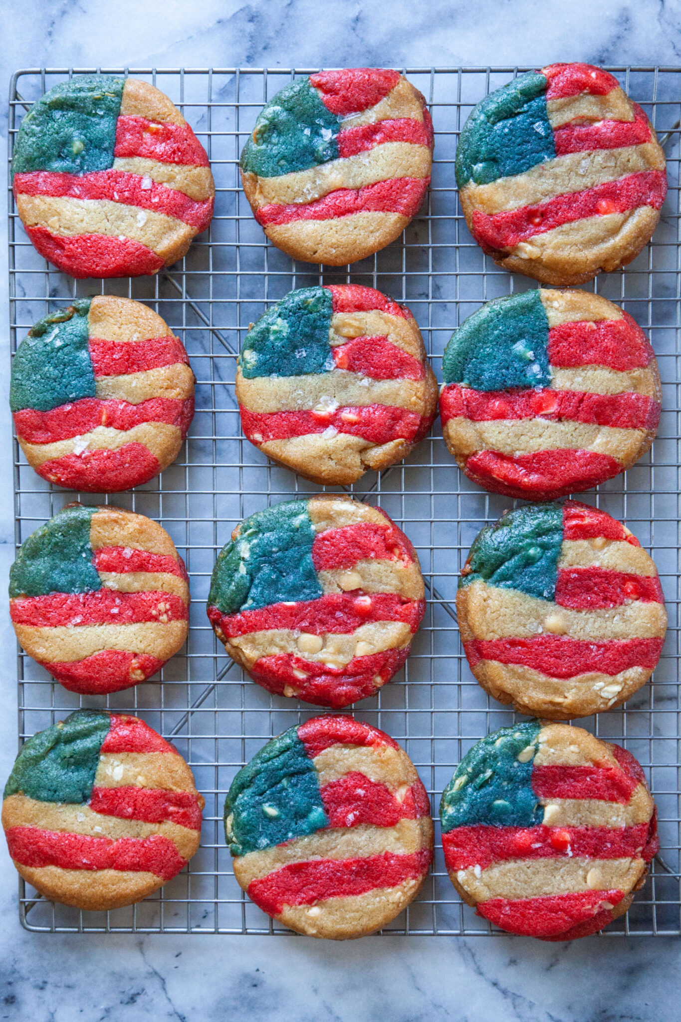 Red, white, and blue American flag-inspired cookies sitting on a wire cooling rack.