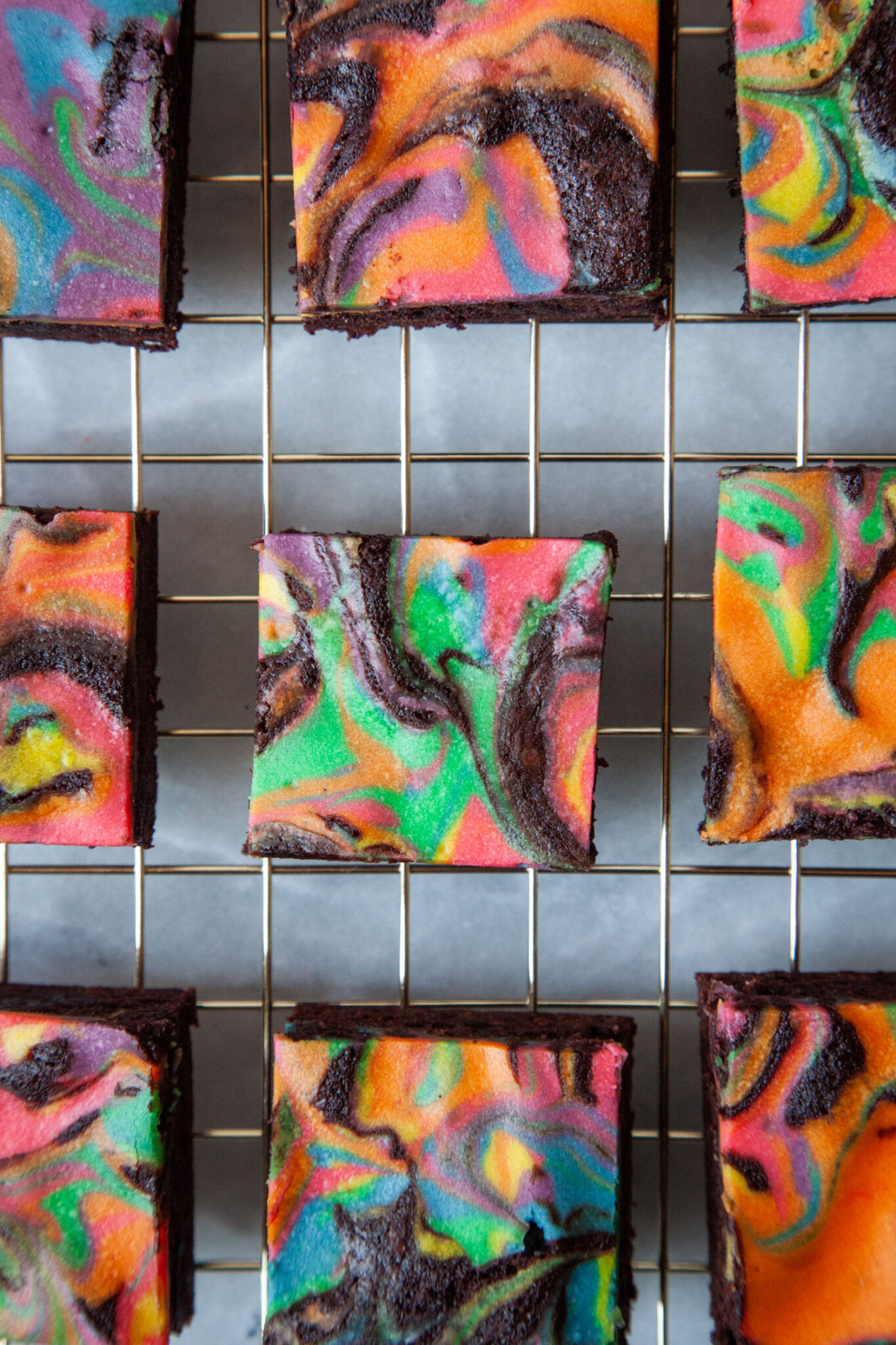 Rainbow cheesecake brownies sitting on a wire cooling rack.