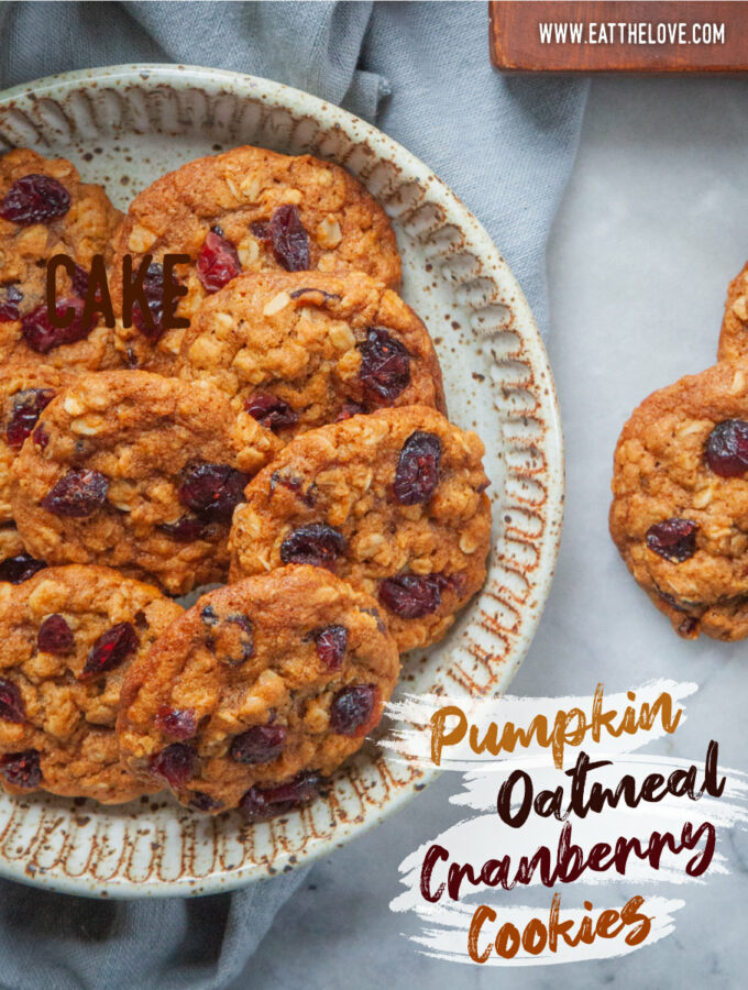 A plate of pumpkin oatmeal cranberry cookies, with more cookies on the table. The text on the image says pumpkin oatmeal cranberry cookies.