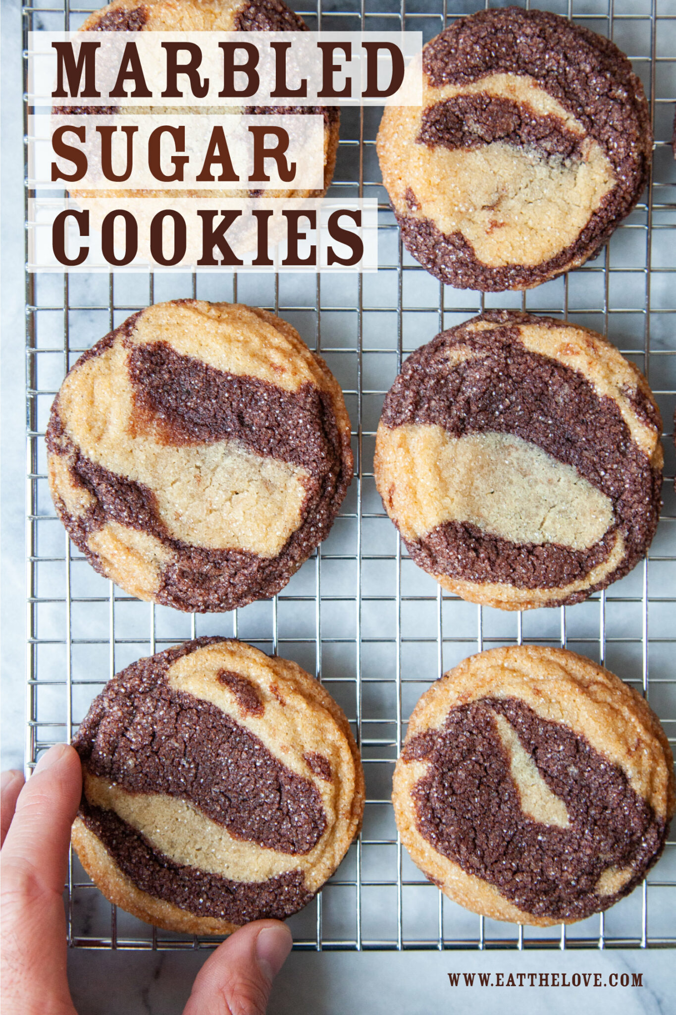 A wire cooling rack of marbled sugar cookies with a hand reaching for one cookie. The text on the image says "Marbled Sugar Cookies".