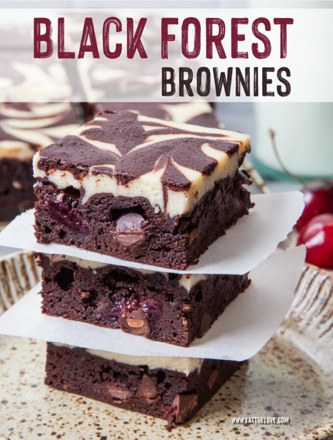 A stack of Black Forest brownies on a plate, with a glass of milk and more brownies behind the plate.