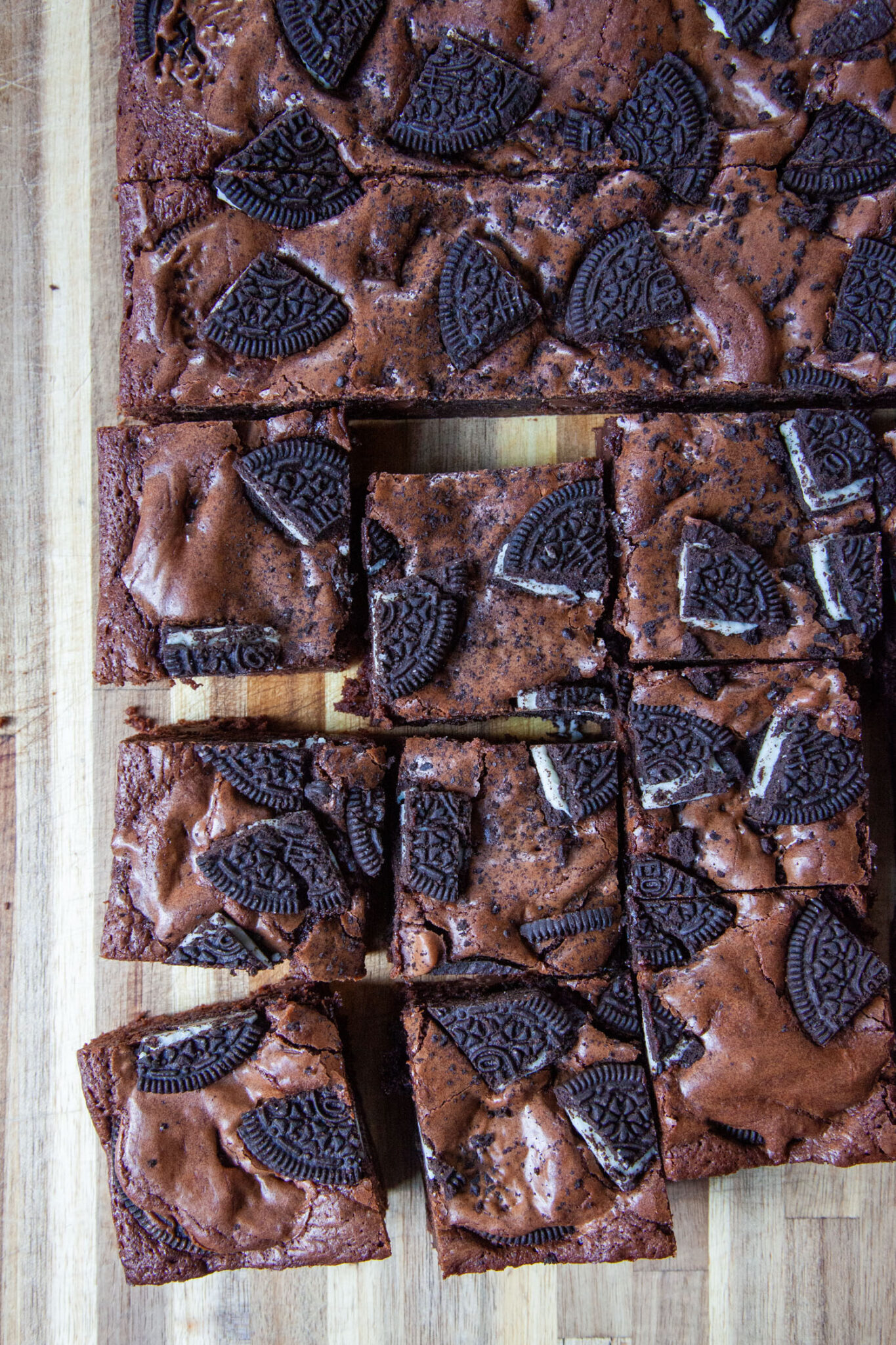 Oreo Brownies cut into squares, sitting on a wooden cutting board.