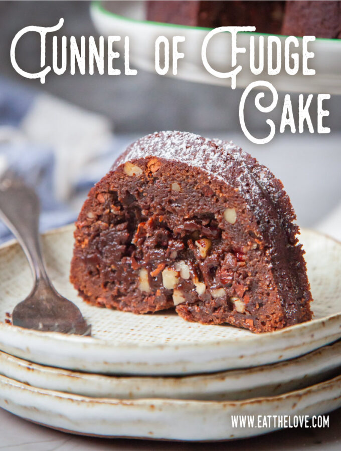 A slice of tunnel of fudge cake on a plate, with the remaining cake behind it on a cake stand.