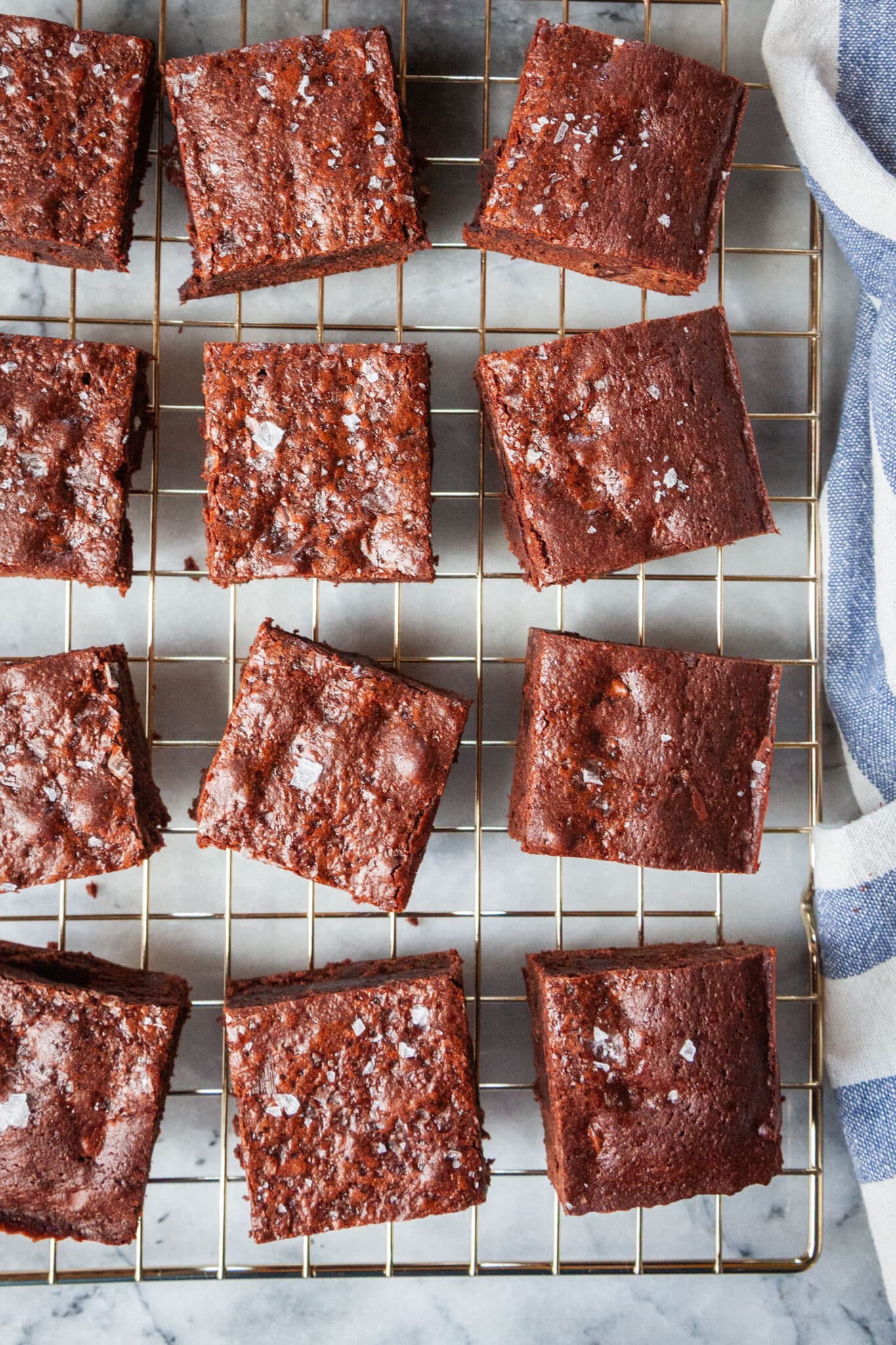 Olive oil brownies with sea salt on a wire cooling rack.