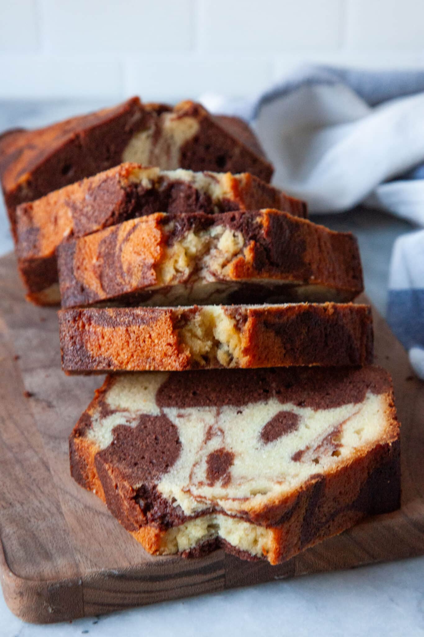 A marbled pound cake sliced on a cutting board.