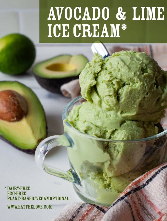 A scoop of avocado and lime ice cream in a glass cup, with a cut avocado and lime behind it.