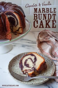 A slice of marble bundt cake on a plate, with the remaining cake behind it on a cake stand. The type on the image says "Chocolate and Vanilla Marble Bundt Cake".