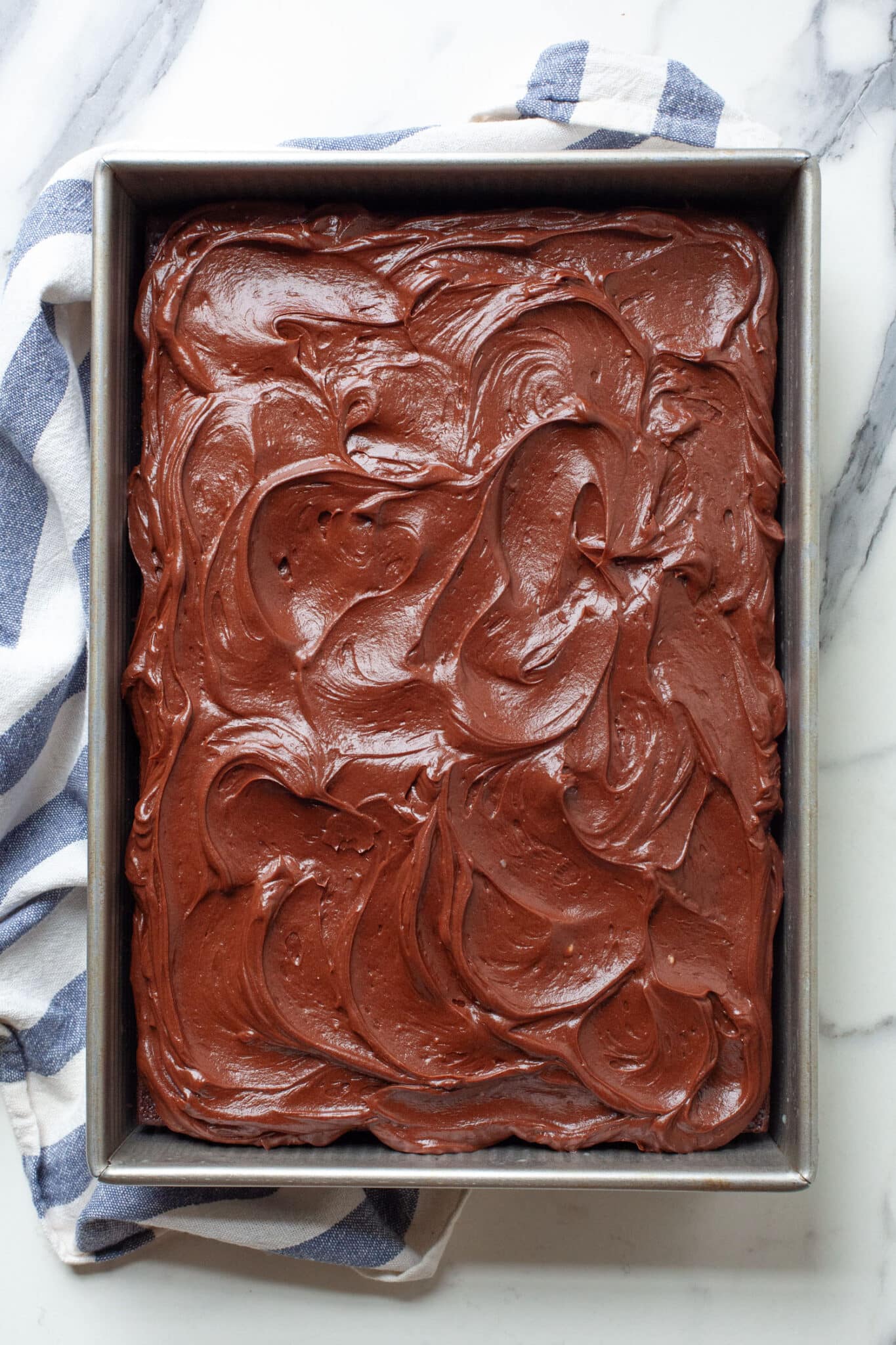 Chocolate mayonnaise snacking cake with sour cream frosting in a pan.